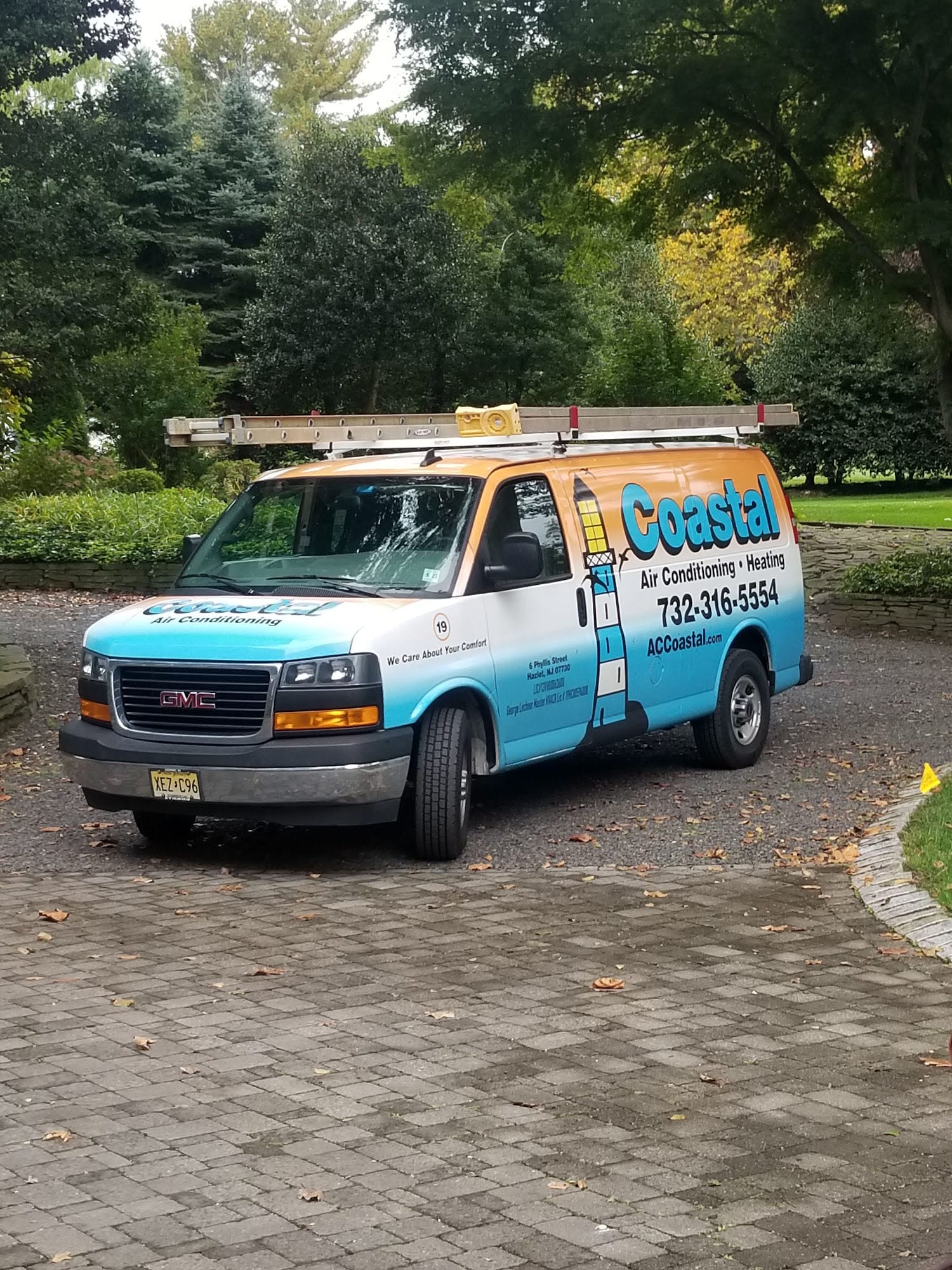 Coastal Air Conditioning GMC service van with ladder parked on a residential driveway